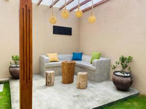 a patio with a couch and some wooden stools at Apa Villa Thalpe in Unawatuna