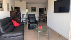 a living room with a black couch and a glass table at Appartement 2 chambres avec balcon terrasse in Villars-sur-Glâne