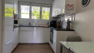 a kitchen with white cabinets and a stove top oven at Appartement 2 chambres avec balcon terrasse in Villars-sur-Glâne