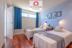 two beds in a room with blue curtains at Infinite View Palamós in Palamós