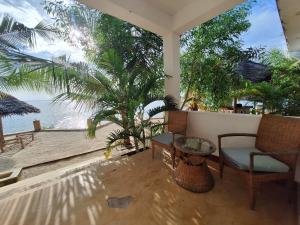 a balcony with a chair and a table and the ocean at Bwereusunsetbungalow in Kidoti