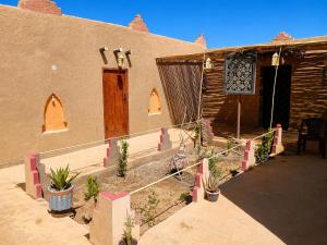 an outside of a building with plants in front of it at Riad dar merzouga in Merzouga