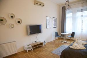 a bedroom with a tv on the wall and two chairs at Five Season's Apartment in Budapest