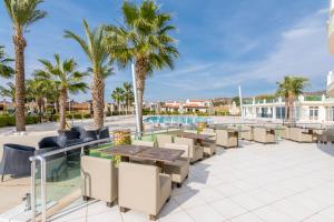 a patio with tables and chairs and palm trees at Apollonium Bozbuk in Akbük