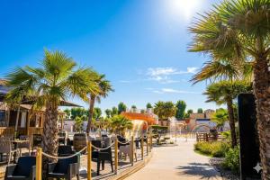 a resort with palm trees and a playground at Les sables du midi in Valras-Plage