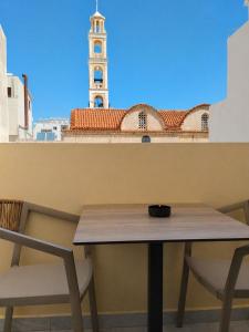 a table and a chair with a clock tower in the background at Morfeas City Hotel in Rhodes Town