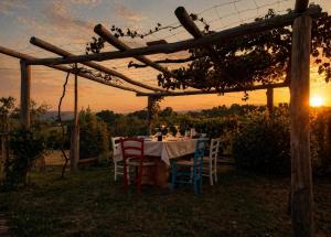 a dinner table under a pergola with the sunset at Agriturismo Podere Sant' Agnese - Suite Apartment in Bibbiena