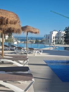 a group of chairs and umbrellas next to a swimming pool at Palm Forest Oasis in Mijas Costa