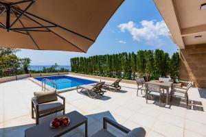 a patio with a table and chairs and a pool at Poljana Olive Homes Pool Residences in Rijeka Reževići