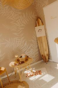 a room with a table and a surfboard on a wall at Adishatz Motel in Biscarrosse