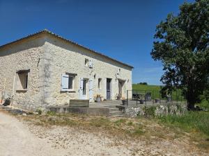 a stone building with a table and a tree at Maison de campagne in Eymet