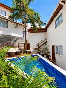 a swimming pool in front of a house with a palm tree at Flats Morro de São Paulo in Morro de São Paulo