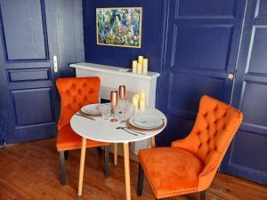 a dining room with a white table and orange chairs at Arthur et Eva - Lit King size - gare - centre - hopital in Abbeville