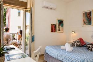 a room with a bed and a table and a woman at INAH Rooms in Dorgali