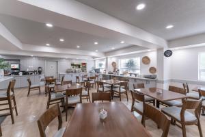 a restaurant with wooden tables and chairs and a kitchen at Prestige Prince George Lodge in Prince George