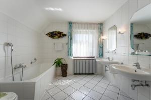 a white bathroom with two sinks and a tub and a toilet at Pension Haus Elmar in Rösrath +32 photos