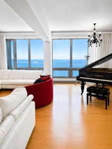 a living room with a white couch and a piano at Premium Seafront Suite in Thessaloniki