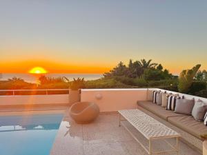a living room with a couch and a sunset at Bay Reflections Camps Bay Luxury Serviced Apartments in Cape Town