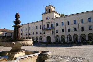 a building with a fountain in front of a building with a clock tower at Pernottamento Madonna del Pino Cervia in Cervia