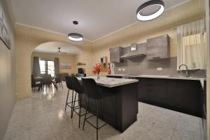 a kitchen with a counter and a bar with stools at Hot Tub With View, Stylish 3BR, Heart of Ghajnsielem in Għajnsielem