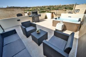 a patio with chairs and a hot tub on a roof at Hot Tub With View, Stylish 3BR, Heart of Ghajnsielem in Għajnsielem