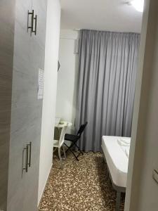 a room with a bed and a table and a window at Pernottamento Madonna del Pino Cervia in Cervia