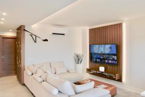 a living room with a white couch and a tv at Tu lugar en la playa in Luanco