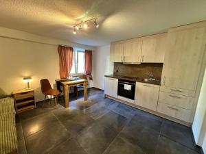 a kitchen with white cabinets and a table and a desk at Hotel Krone in Wassen