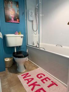 a bathroom with a toilet and a bath tub with a sign that says help at Well St Apartment in Moffat
