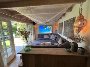 a bedroom with a bed and a couch and a tv at Unique Accommodation in Twente with Jacuzzi in Borne