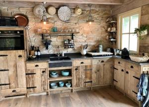 a kitchen with wooden cabinets and a stone wall at Unique Accommodation in Twente with Jacuzzi in Borne
