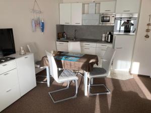 a kitchen with a table and four chairs and a television at Kiek mol wedder in in Borkum +26 photos