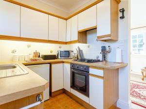 a kitchen with white cabinets and a stove top oven at 2 Bed in Beaworthy oc-77555 in Black Torrington