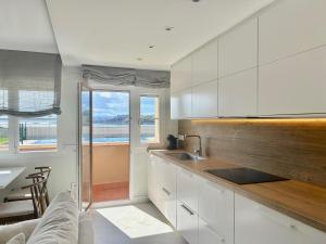 a kitchen with white cabinets and a view of the ocean at Tu lugar en la playa in Luanco