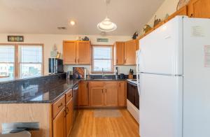 a kitchen with wooden cabinets and a white refrigerator at Carolina Kai, Kitty Hawk MP 3, 275 Yds to Beach, Ocean View, Pool, Hot Tub, Flex Stays in Kitty Hawk