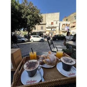 a table with two cups of coffee and croissants and drinks at Boteco B&B in Bacoli