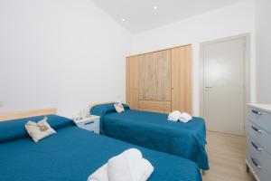 a bedroom with two blue beds and a dresser at Villetta Caterina in Procida