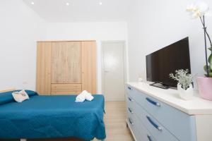a bedroom with a blue bed and a tv on a dresser at Villetta Caterina in Procida
