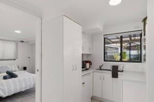 a white bedroom with a bed and a window at Bayview Nook Tanilba Bay in Lemon Tree Passage