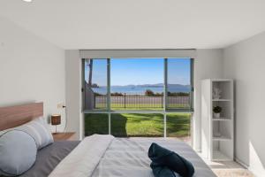 a bedroom with a bed and a large window at Bayview Nook Tanilba Bay in Lemon Tree Passage