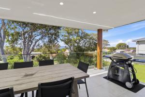 an outdoor patio with a wooden table and a grill at Lakeview Luxury in Budgewoi