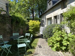 a patio with a table and chairs next to a building at La Maison des Rues Pavées avec jardin by La Boîte En Plus in Senlis