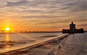 a sunset over a pier with a lighthouse and a bridge at Lovely Stacaravan In La Tremblade in La Tremblade +20 photos
