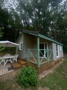 a small green cabin with a table and a patio at Chalet cosy in Lissac-sur-Couze +1 photo