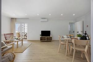 a living room with a table and a television at Casinha da Praia da Rocha in Praia da Rocha