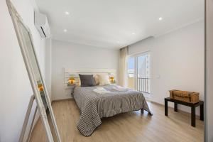 a white bedroom with a bed and a window at Casinha da Praia da Rocha in Praia da Rocha