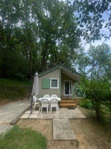 a small house with a table and chairs and an umbrella at Chalet cosy in Lissac-sur-Couze