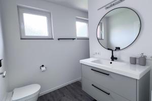 a white bathroom with a sink and a mirror at Emsland-Hus WG2 in Niederlangen +5 photos