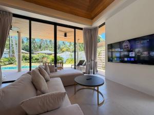 a living room with a large couch and a tv at MoonLight Villa - 3BR Tropical Pool Retreat in Ko Phangan