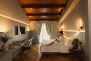 a woman sitting on a bed reading a book at Masseria Pietrafitta in Foggia